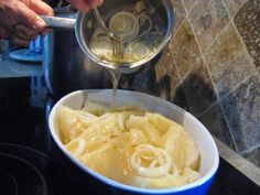 someone is pouring sauce over some noodles in a blue bowl on top of the stove