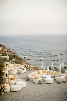 an outdoor seating area overlooking the ocean with umbrellas and chairs set up for guests