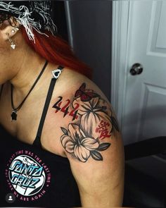 a woman with red hair wearing a black tank top and flower tattoos on her arm