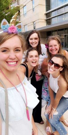 a group of young women standing next to each other in front of a tall building