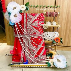 a red and white sari with flowers on display in front of a wooden wall