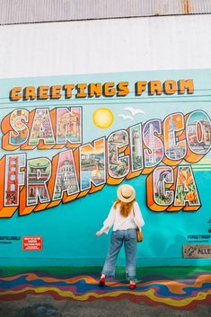 a woman standing in front of a colorful wall with the words san francisco written on it