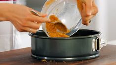 a person scooping something out of a pot with a spoon in it on top of a wooden table