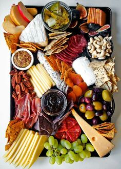 an assortment of cheeses, crackers, and meats on a platter