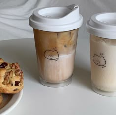 there are two cups with drinks and cookies on the table next to eachother