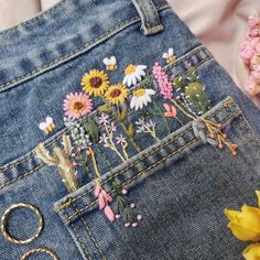 a pair of scissors and some flowers in the pocket of someone's jean shorts