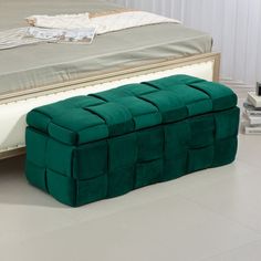 a large green ottoman sitting on top of a white floor next to a bed and nightstand