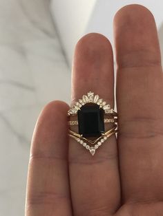 a woman's hand holding a ring with a black stone and diamond set in it