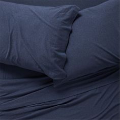 a bed with blue sheets and pillows on top of it