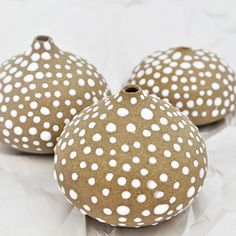 three brown vases with white polka dots on them sitting on a piece of paper