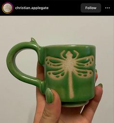 a hand holding a green mug with a dragon on it