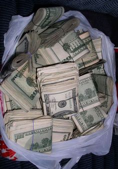 a bag filled with lots of money sitting on top of a bed covered in plastic