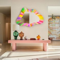 a living room with a pink table and mirror