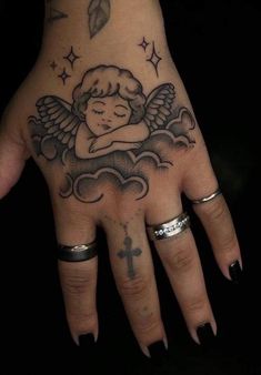 a woman's hand with an angel tattoo and cross on the middle finger,