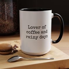 a coffee mug with the words lover of coffee and rainy days on it next to a spoon