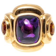 14k yellow gold ring. This impactful ring has a rectangular sugarloaf cabochon cut dark purple color amethyst center, bezel set and flanked by two oval faceted, dark orange color citrines, approximately 0.18 TCW, also bezel into a chunky, contemporary rectangular profile mounting. Marks: 14k Dimensions: 13/16" across the top x 11/16" wide Weight: 9.3 gross dwt Ring Size: 6.5 Dark Orange Color, Amethyst Cocktail Ring, Dark Purple Color, Yellow Gold Cocktail Ring, Amethyst And Citrine, Amethyst And Diamond Ring, Gold Cocktail Ring, Gold Cocktail, Citrine Ring