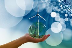 a hand holding a glass ball with a wind turbine in it