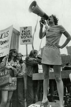 a woman speaking into a megaphone while standing in front of a group of people