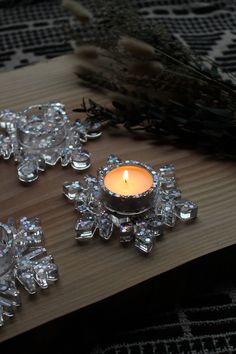 a candle that is on top of a wooden table next to some crystal ornaments and a pine branch