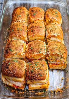 a glass baking dish filled with sandwiches covered in parmesan cheese and seasoning