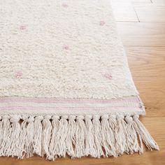 a large white rug with fringes on the floor in front of a wooden floor