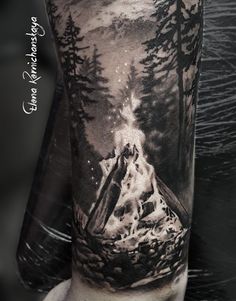 a man's arm with a black and white tattoo on it, depicting a mountain scene