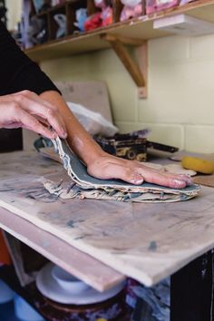 a person with their hands on a piece of wood that is being sanded down