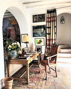 a living room filled with lots of furniture and pictures on the wall next to a table