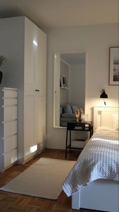 a bedroom with a bed, desk and white cupboards in front of the window