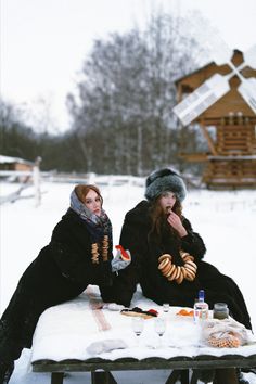 two women sitting at a picnic table in the snow