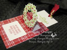 a red and white card with a christmas wreath on it next to a folded envelope