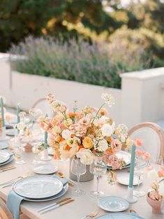 the table is set with plates and flowers in vases, candles and napkins