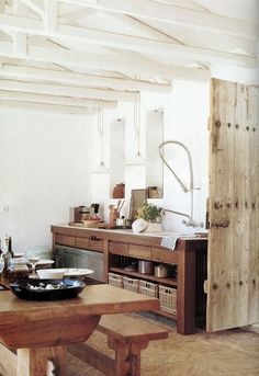 a wooden table sitting in front of a kitchen with lots of counter space and cabinets