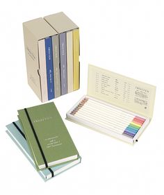 three books and two notebooks with colored pencils in front of them on a white background