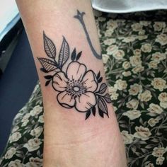 a black and white flower tattoo on the left arm with an arrow in the middle