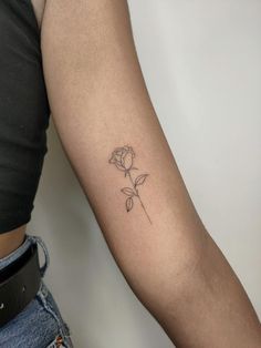 a woman's arm with a single rose tattoo on the left side of her arm