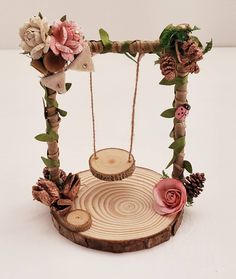 a wooden swing with flowers and pine cones on it