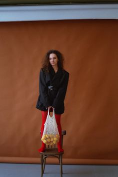 a woman standing on top of a chair holding a bag