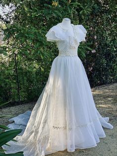 a white wedding dress on display in front of trees