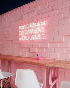 pink brick wall with neon sign and chairs