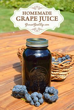 a blue mason jar sitting on top of a wooden table with grapes in front of it