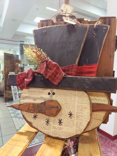 a wooden snowman sitting on top of a wooden sleigh with a pirate ship in the background