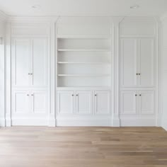 an empty room with white cabinets and wood floors