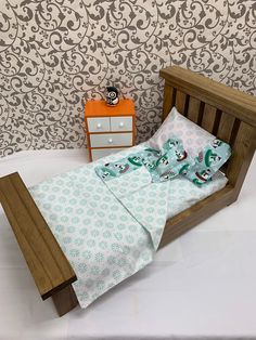 a small bed with two pillows on top of it next to a dresser and wallpaper