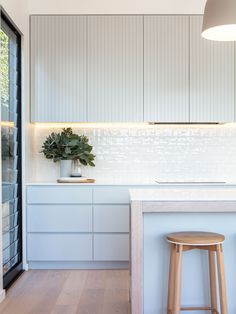 a kitchen with an island and stools in front of the counter top, along with white cabinets