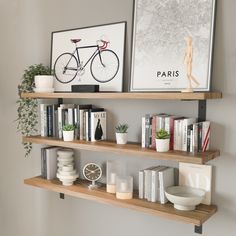 two wooden shelves with books, vases and pictures on them