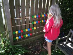 a woman standing in front of a wooden fence with colorful buttons attached to the board