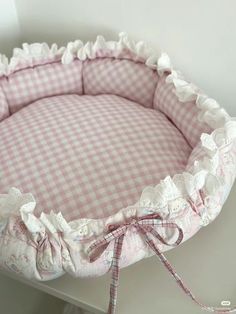 a pink and white checkered dog bed with ruffled edges