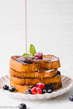 a stack of french toast topped with berries and syrup