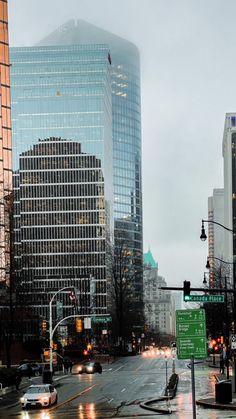 a city street filled with lots of traffic next to tall buildings on a cloudy day